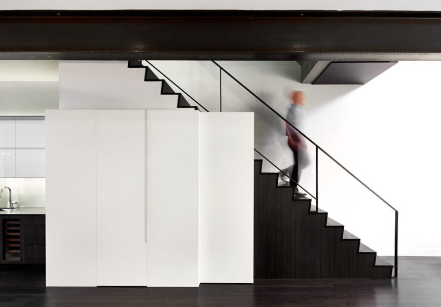 Head-on view of staircase, highlighting black and white contrast, with exposed metal I-beam at top.