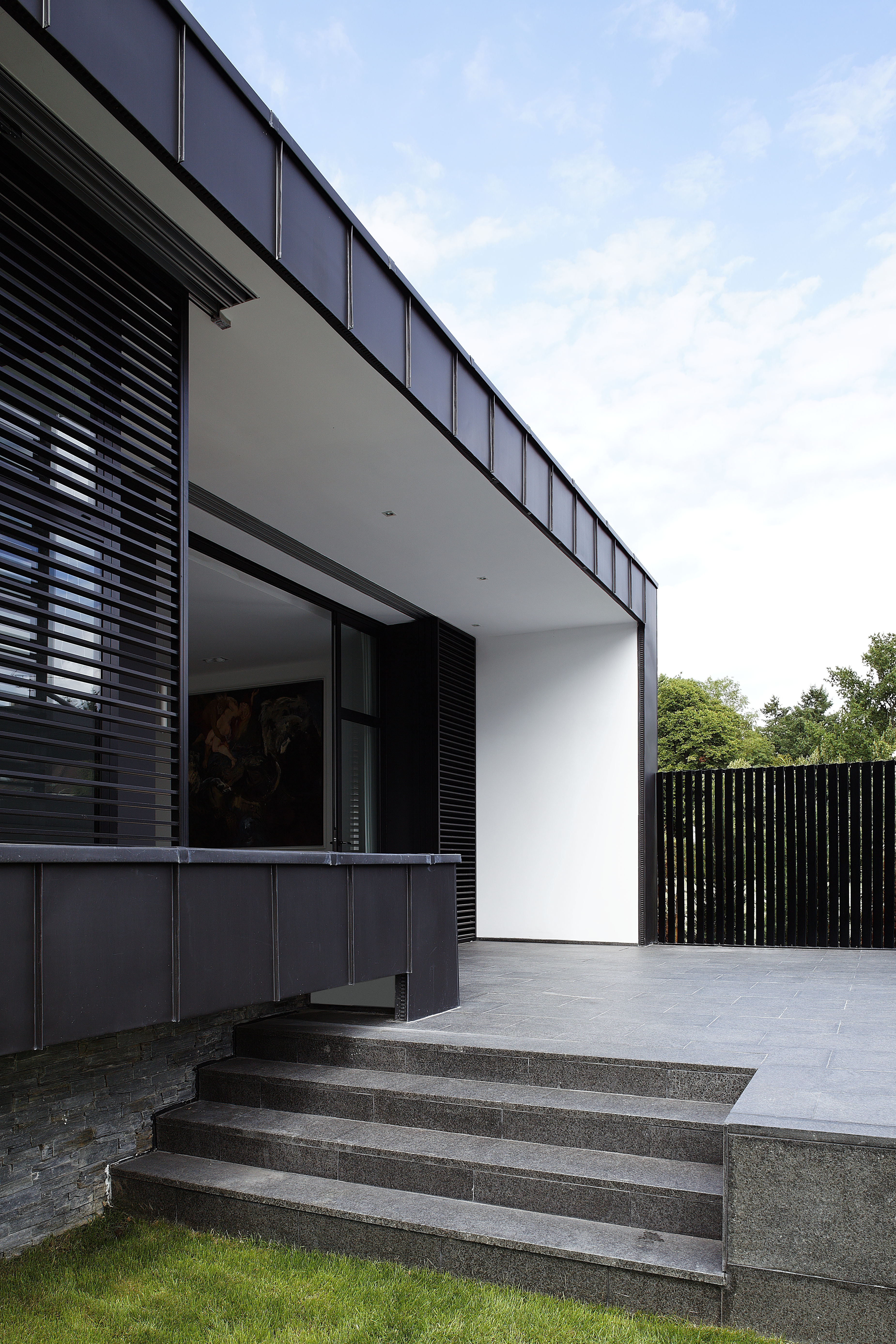 The stone patio connects seamlessly with indoor flooring through the living room, seen through large sliding glass door at left.