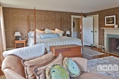 The primary bedroom combines stripes, florals, and geometric patterns with hardwood floors and recessed lighting around the perimeter of the room.