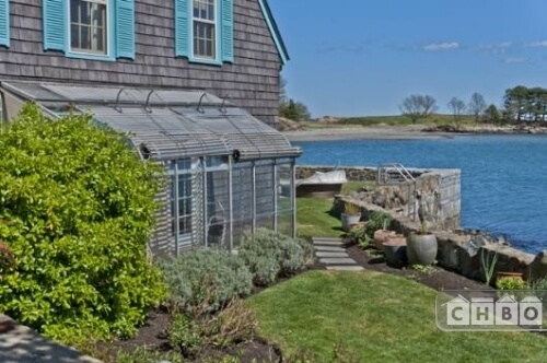 An outside view of the greenhouse and the sea wall. The wall has a ladder to go down to the shore.