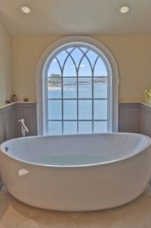 A close up of the bathtub displaying the amazing view outside of the window.