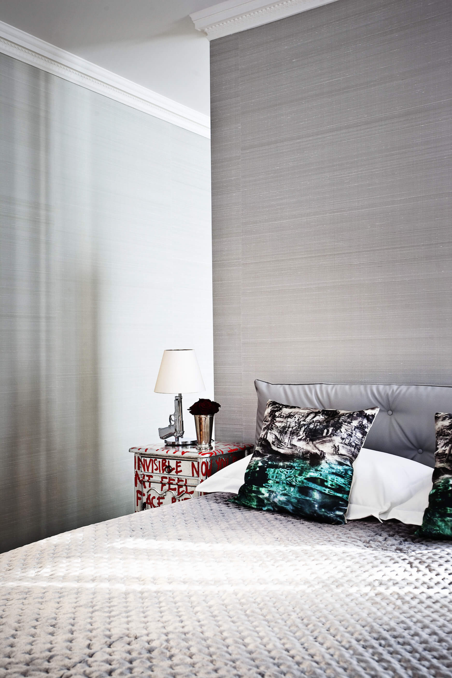 Another bedroom, in a complete turn of style, stands out in silver tones, with brushed look walls above a uniquely textured bed set.