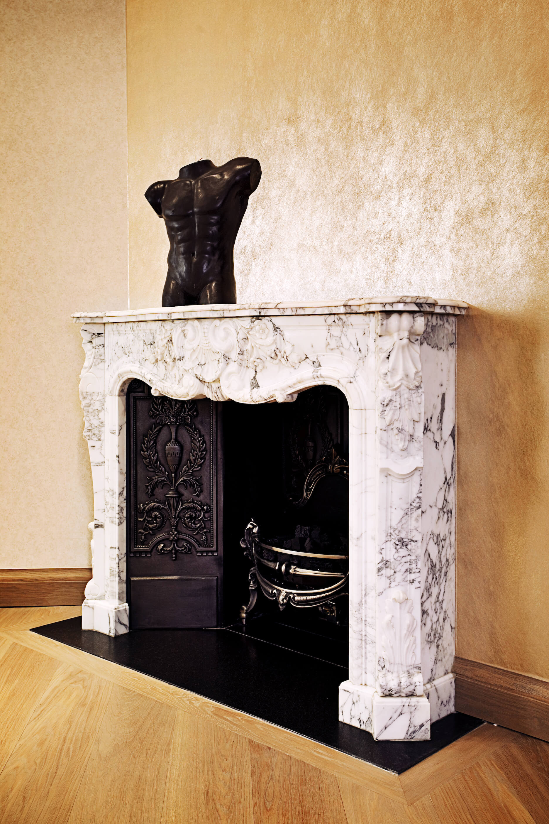 Standing within the dining room, this marble wrapped fireplace stands out with its bright, contrasting tones and rich, carved details. 