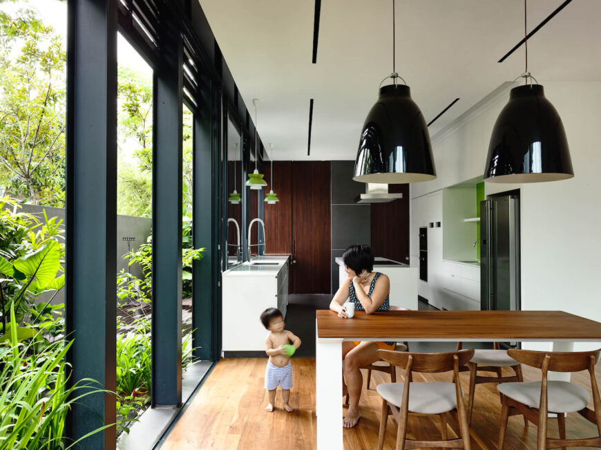 Behind the living room is a small dining room with a white and natural light wood table directly adjacent to the minimalist kitchen.