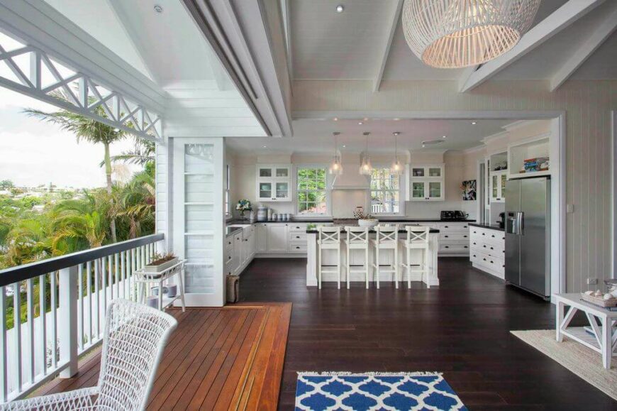 The balcony is included in the area. The glass doors can be pulled shut to enclose the main portion of the house during less than beautiful weather. From this angle, we can see the entirety of the spacious U-shaped kitchen with custom cabinetry and an eat-in kitchen bar.