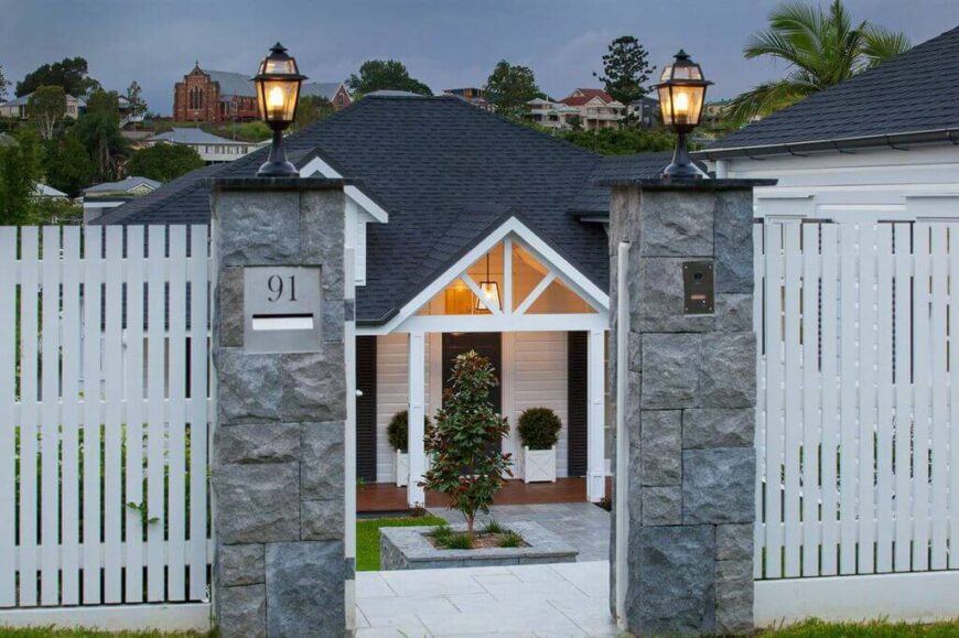  A view of the front of the home from just outside the opened gates. The single-story home has an elegant pathway leading up to the porch, with only ornamental trees so that the home gets as much sunlight as possible.