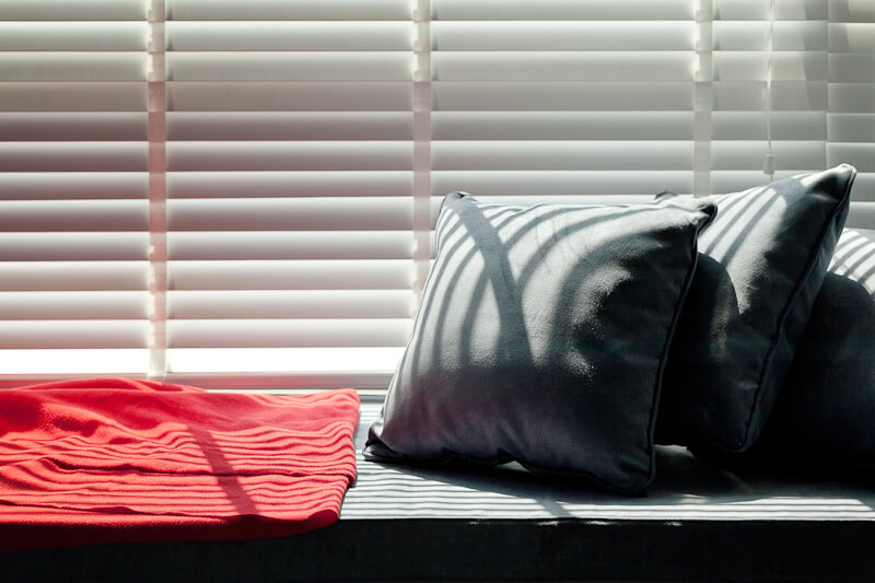 A small window seat relaxing space sits below the large full-height window in the bedroom.