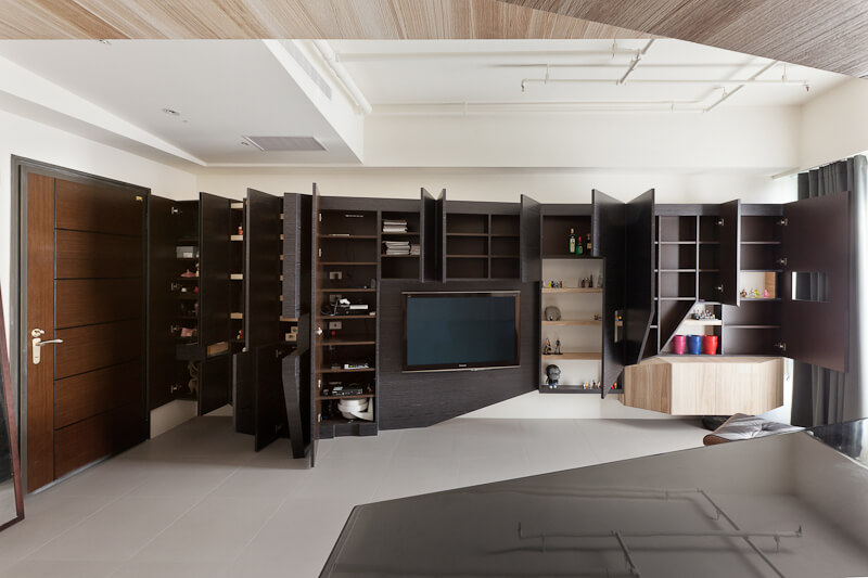 Turning toward the living room, we see how the wall-length expanse of angular cabinetry looks when fully opened, revealing an abundance of storage options.