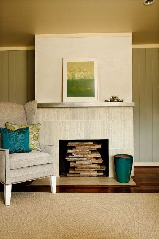 A close up of the fireplace, showcasing the stacked wood that fills the open, unused hearth.