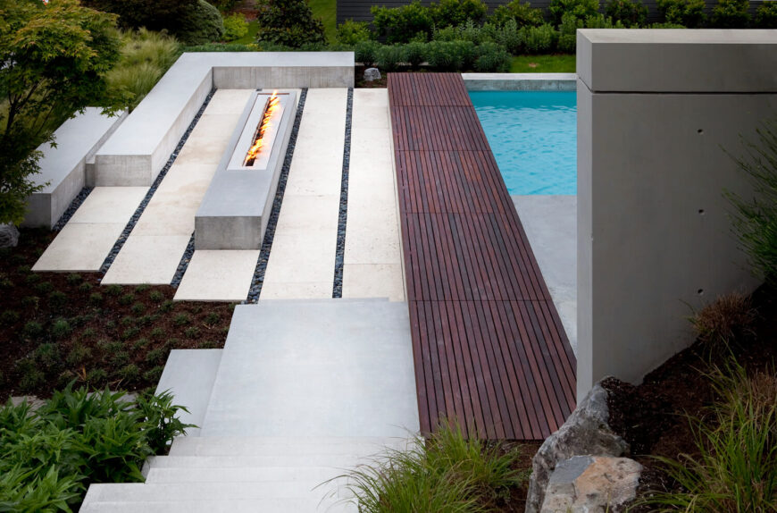 Looking down toward the patio, we see rich wood panels bisecting the concrete expanse. A unique outdoor gas fireplace strip stands across form the pool, at left.