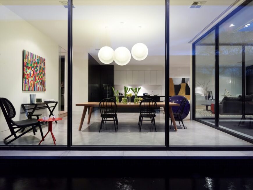 Viewing the large open central interior space through wraparound glazing, we see an abundance of sharp textural details set against the white walls and marble flooring. The dining, living, and kitchen areas share this space.