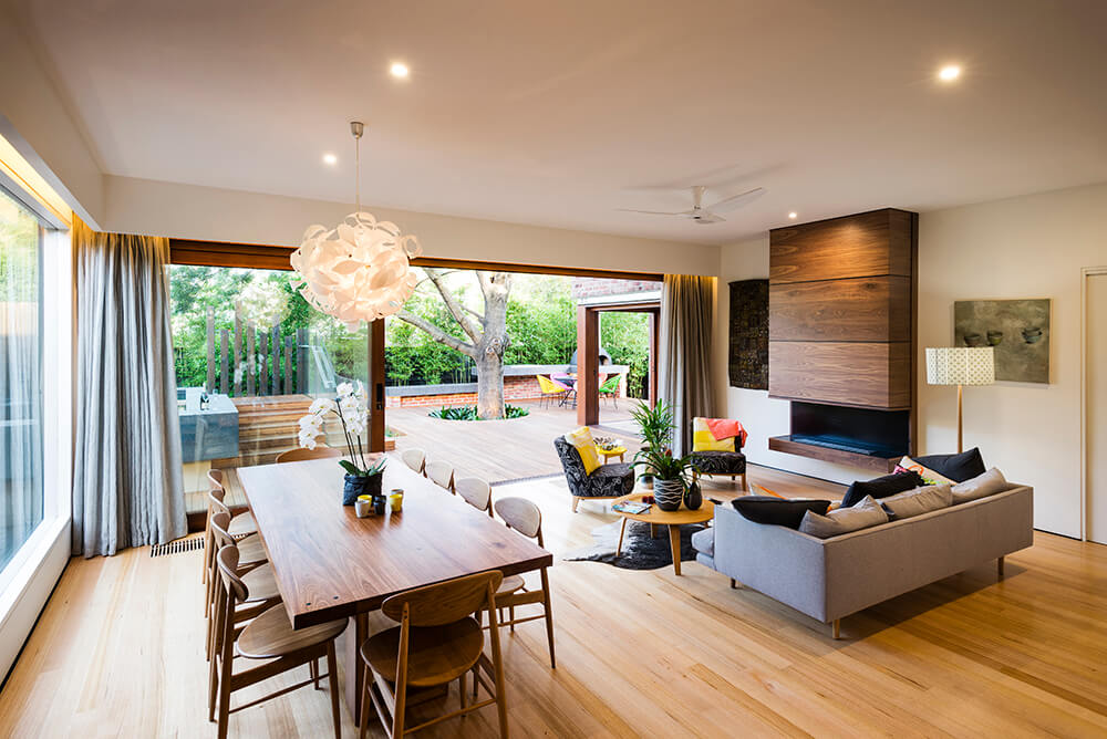 Contemporary dining space with a lovely chandelier that hung over wooden dining set along with hardwood flooring.