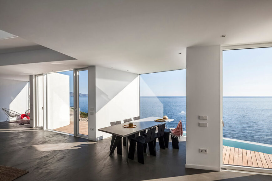 One of the cubes juts out from the main living area and contains a large dining table. The whole of the space is utterly undecorated, allowing the stunning views to take precedent. To the left we can see the sliding glass doors that provide access to the patio and pool area.