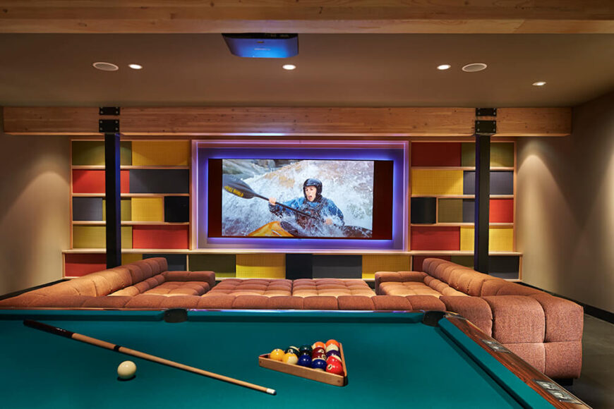 The rec room is a nice hideaway to relax and unwind. The built-in screen for the ceiling-mounted projector is surrounded by fun, colorful wall decor. The large couch offers plenty of room for family and guests to enjoy a movie while the billiards table in the foreground provides a different kind of fun.