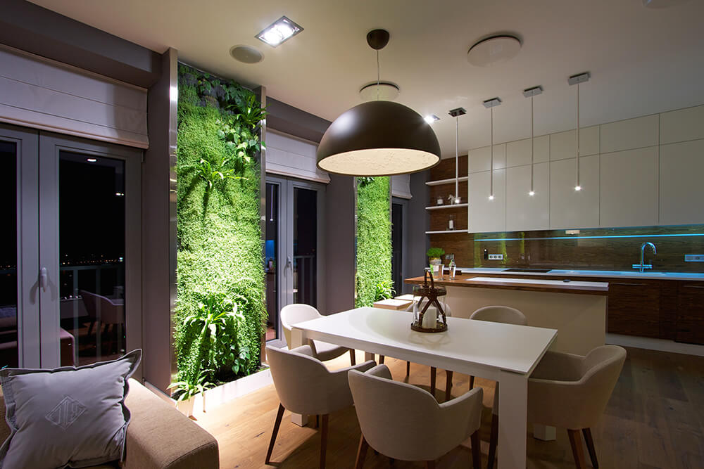 An oversized pendant lamp lit this small dining space. It has hardwood flooring and vertical garden panels that add tropical vibes to the area.