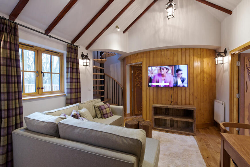 A spiral staircase leads back down to the main living area, where we can see the door to the bathroom and a large television.