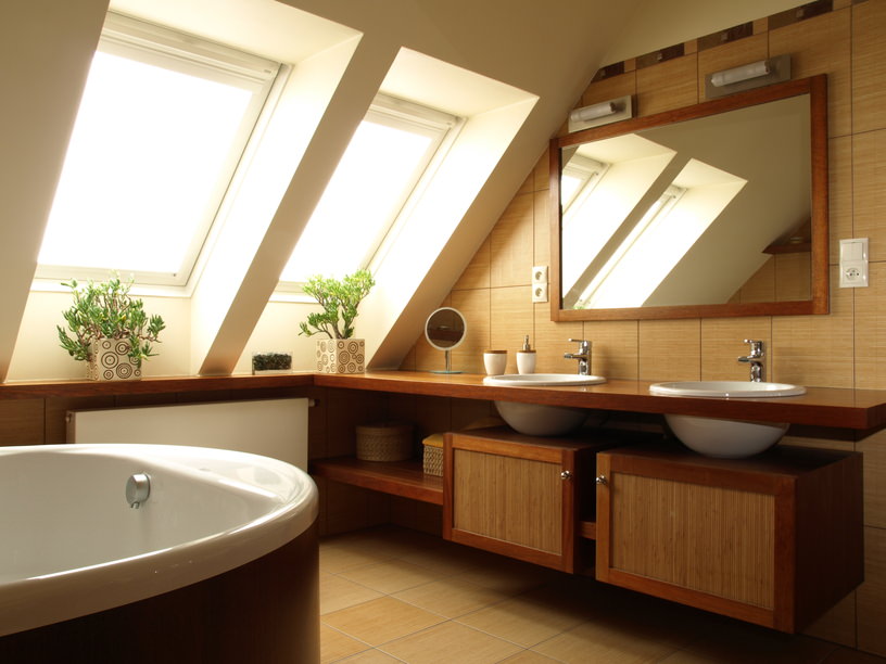 Large awning windows bring in plenty of natural light to primary bathroom which features two vessel sink bowls set in a floating vanity. The space also includes a soaker tub, wall-mounted lights over the vanity and ceramic tile flooring.