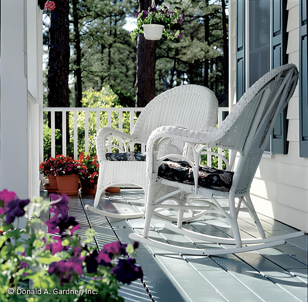 Covered porch with wicker rocking chairs over the wide plank flooring.