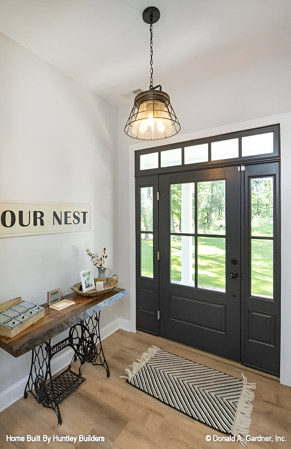 Foyer with a glazed entry door, a tasseled rug, a dome pendant, and a vintage console table.