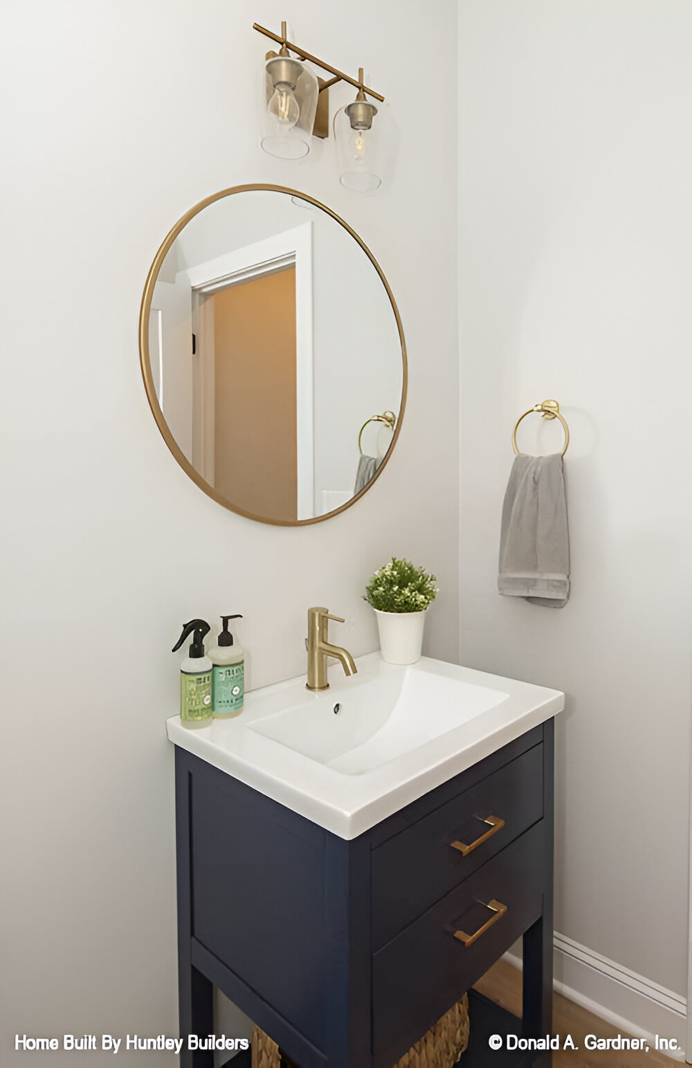 Powder room with a dark washstand and a brass round mirror.