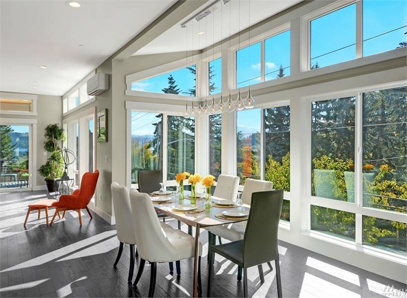 Contemporary dining room with a rectangular dining table and mismatched chairs. Floor-to-ceiling windows flood the room with natural light. 