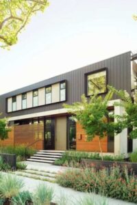 The landscaping of this Palo Alto, CA, residence features hanging ferns, planted shrubs and grasses, as well as mature trees scattered throughout the property.