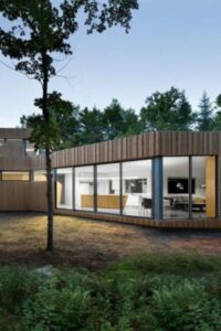 Canadian lakefront home, nestled into a woodland setting, features a cedar wood slat exterior with large windows to draw in natural light.