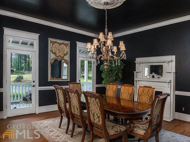 This medium-sized dining room still manages to be bright despite its black walls and ceiling. This is due to the abundance of natural lighting that comes in through the two glass doors flanking a wall-mounted mirror that faces the wooden dining table and its wooden chairs with floral cushions.