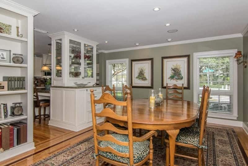 The seats of the wooden chairs have animal print patterns on it that complements the patterned area rug over the hardwood flooring that matches with the dining table. This is given a nice background of light green walls and white wooden structures.