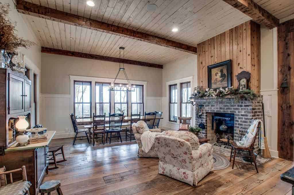 The simple and homey aura of this medium-sized dining room is augmented by the sitting area beside it that has a classic bricked fireplace. The long rectangular wooden table matches with the hardwood flooring and then paired with wooden chairs.