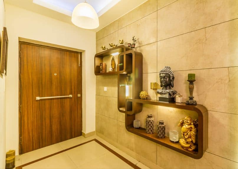 This simple Asian-style foyer maximizes its small space with built-in shelves that are mounted on the white marble wall on the right. The wooden shelves are arranged in a unique manner and are augmented by various Asian decors that would elevate the simple foyer.