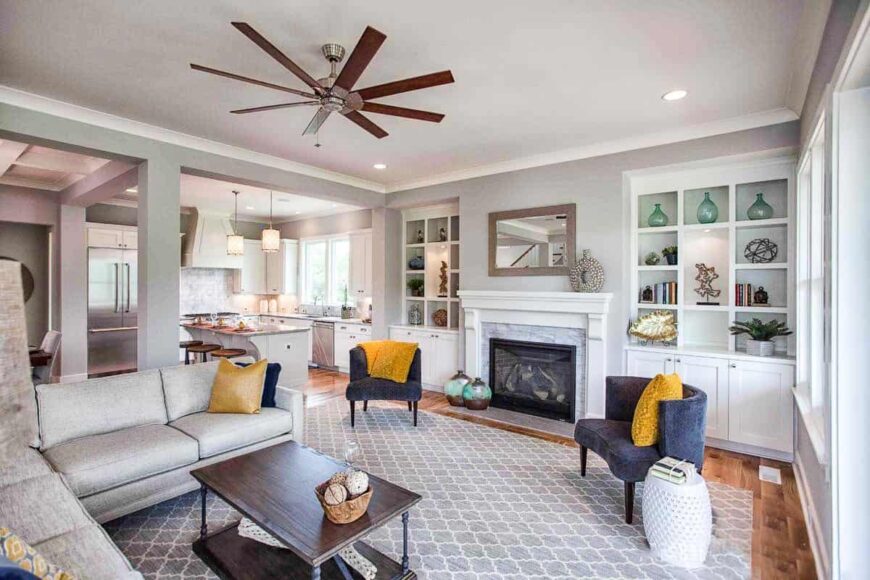 The living room has gray seats, a patterned area rug, and a fireplace flanked by built-ins.