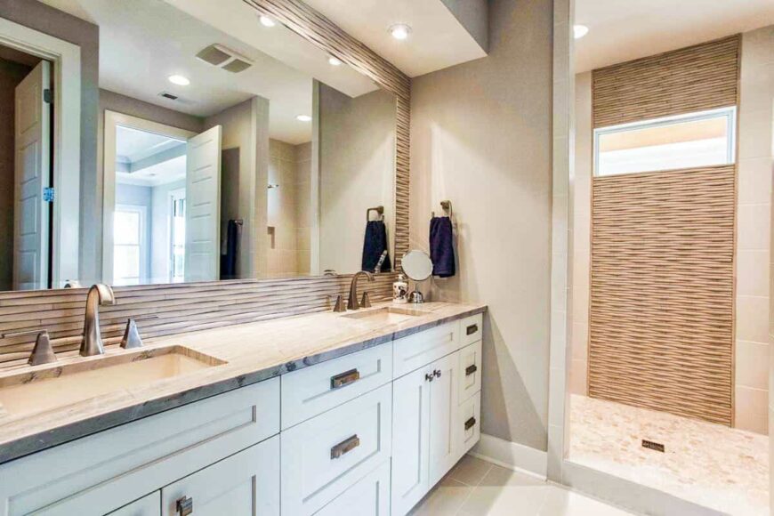 Primary bathroom with a shower area, and dual sink vanity paired with a large frameless mirror.