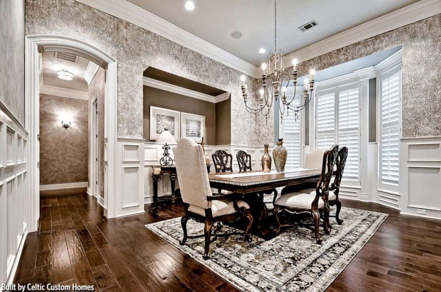 A closer look at the dining room shows the dark wood dining table under the candle chandelier and a buffet bar against the inset wall.