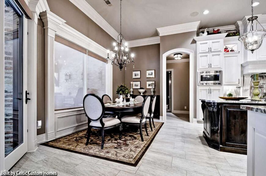 The breakfast nook offers a candle chandelier, and oval dining table, and round back chairs over a classic area rug.