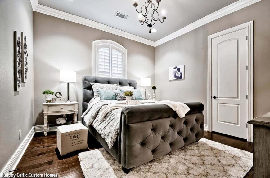 This bedroom offers a cozy tufted bed flanked by white nightstands and drum table lamps.