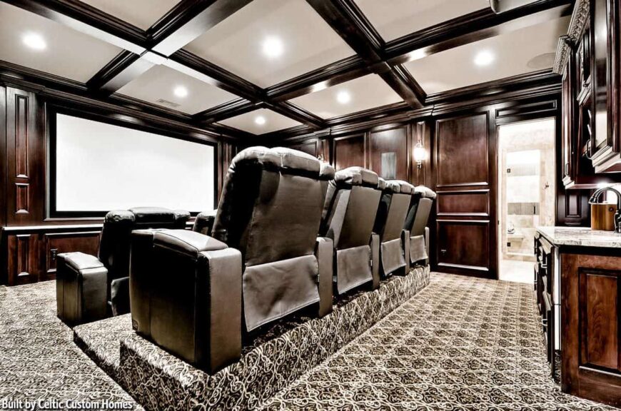 The home theater has lovely carpet flooring and a coffered ceiling fitted with recessed lights.