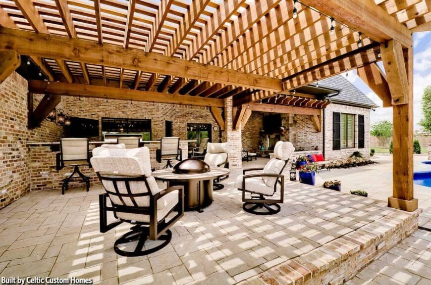 Covered lanai across the kitchen with cushioned armchairs surrounding the round center table.