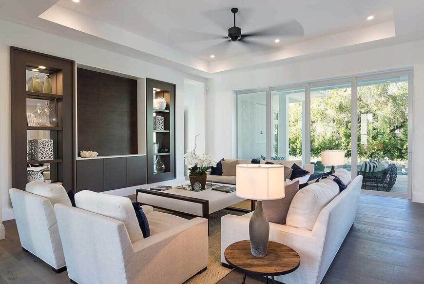 Living room with a tray ceiling and a dark hardwood flooring matching with the built-ins.