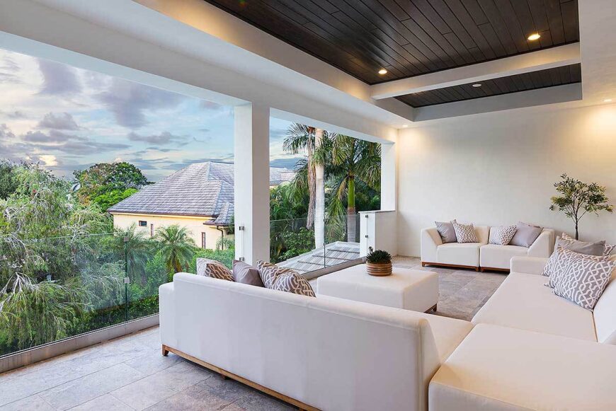 The balcony enclosed in frameless glass railing overlooks the expansive greenery.