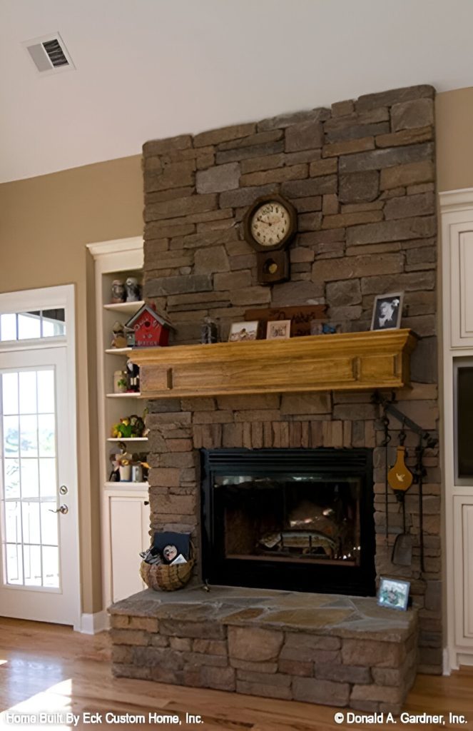 A closer look at the stone fireplace flanked by white cabinets.