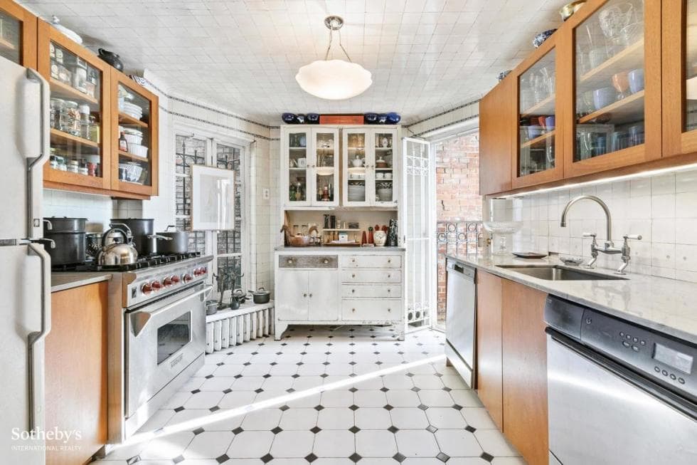 This is the bright and white kitchen with patterned flooring tiles, wooden cabinetry and stainless steel appliances. Image courtesy of Toptenrealestatedeals.com.