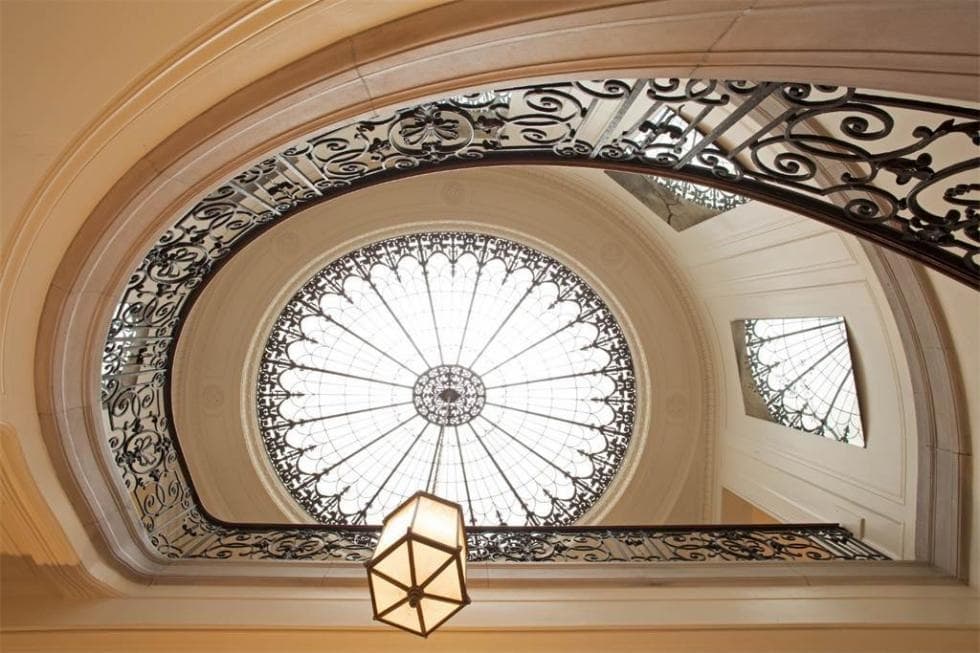 This is the tall ceiling of the foyer. It has a large glass dome at the top that also hangs a large lantern pendant light over the indoor balcony with wrought-iron railings. Image courtesy of Toptenrealestatedeals.com.