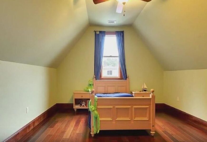 This bedroom has a vaulted ceiling, wooden furnishings, and bright yellow walls.