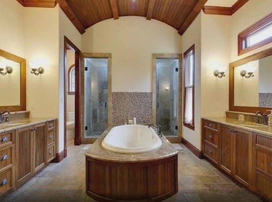 The primary bathroom has two vanities, a toilet room, a deep soaking tub, and a spacious walk-in shower with two glass doors.