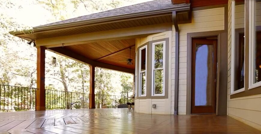 The covered porch transitions to an open deck with hardwood flooring arranged in a chevron pattern.