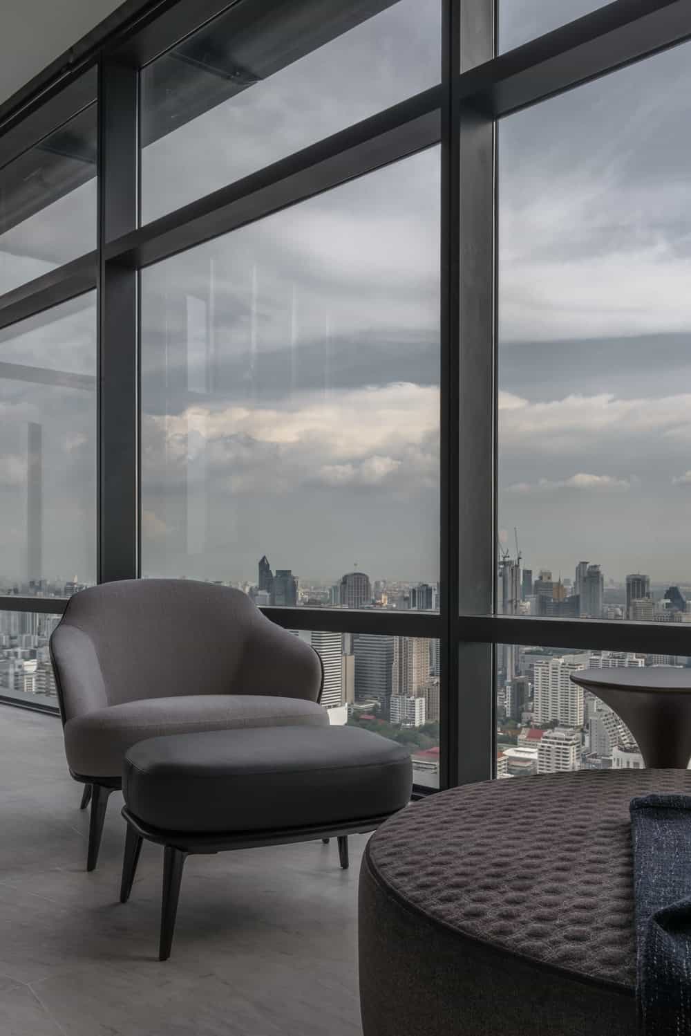 The gray cushioned armchair of the sitting area is paired with a matching footrest and a dark coffee table.