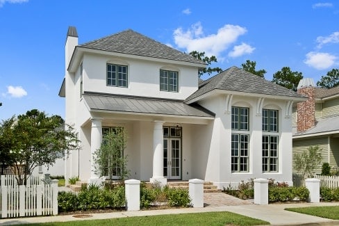 Front exterior view showing the stucco siding, white french doors, and a covered porch lined with large columns.