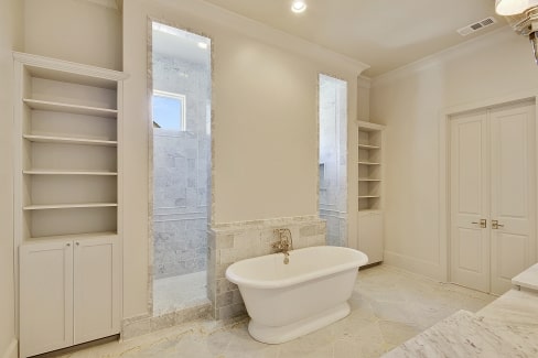 The primary bath is equipped with marble top vanity, white built-ins, a freestanding tub, and a spacious walk-in shower.