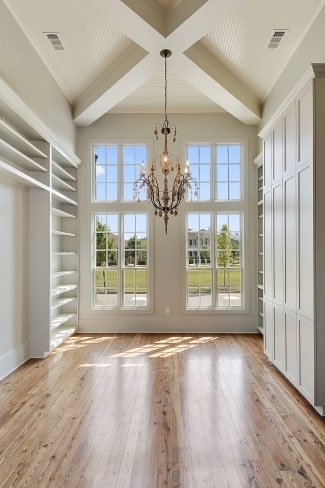 Dining area with white built-ins, an ornate chandelier, and tall windows that invite natural light in.